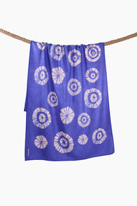Blue tie-dye shibori sand-free beach towel with circular pattern on a rope display 